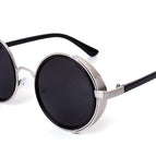 Marco plateado y lentes grises.